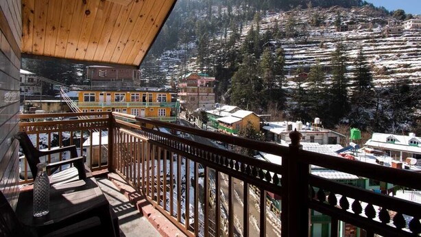 A balcony with a view of a snow-covered village and mountains. - Crystal Mountain Jibhi (Banjar)