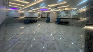 A spacious lobby with a patterned floor, seating area with blue chairs, and decorative wall panels. - Blue Sky Hotels and Banquets  (Kanpur)