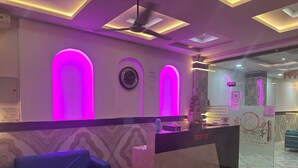 A reception area with a reception desk, a blue sofa, and a clock on the wall. - Blue Sky Hotels and Banquets  (Kanpur)