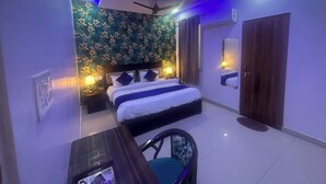 A bedroom with a bed, bedside lamps, a ceiling fan, and a mirror. - Blue Sky Hotels and Banquets  (Kanpur)