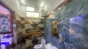 A bathroom with a marble wall, a sink, and a toilet. - Blue Sky Hotels and Banquets  (Kanpur)