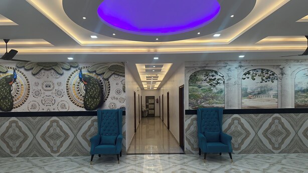 A hotel lobby with a peacock-themed wall, two blue armchairs, and a marble-patterned floor. - Blue Sky Hotels and Banquets  (Kanpur)