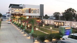 A modern hotel with a well-lit entrance, outdoor seating, and a sign reading "SHIVANTA".