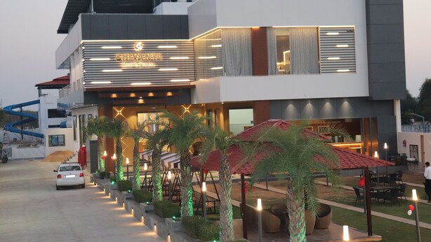 A modern hotel with a prominent sign, outdoor seating, and a well-lit entrance.