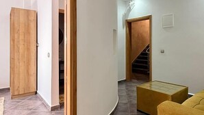 A modern interior with a curved wall, a wooden door, a staircase, and a yellow sofa. - Playa Surf House (Aourir)