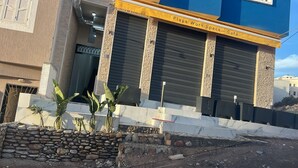 A building with a stone facade, a closed shuttered entrance, and a sign reading "Playa Work Space Café". - Playa Surf House (Aourir)
