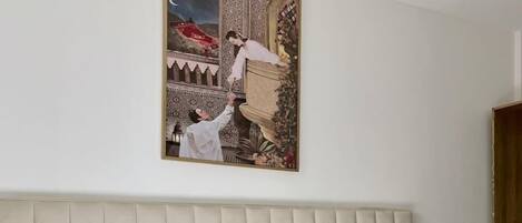 Un dormitorio con cama, mesita de noche, cuadro colgado en la pared y puerta de madera.