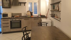 Una cocina compacta equipada con microondas, estufa, horno y un comedor con mesa y sillas.