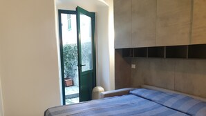 Un dormitorio con cama, armario y puerta que da a un balcón.