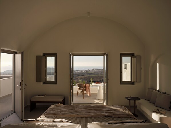 Une chambre avec un grand lit, un banc et une table offrant une vue sur la campagne.