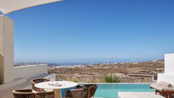 A terrace with a pool, wicker chairs, and a table with a bottle and glasses.