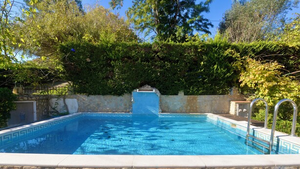 A rectangular swimming pool with clear blue water, surrounded by a stone wall and lush greenery. - Casa Bianca (A dos Francos)