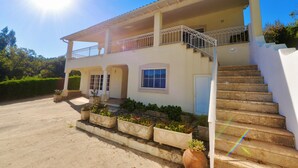 A two-story house with a balcony, a staircase, and a driveway. - Casa Bianca (A dos Francos)