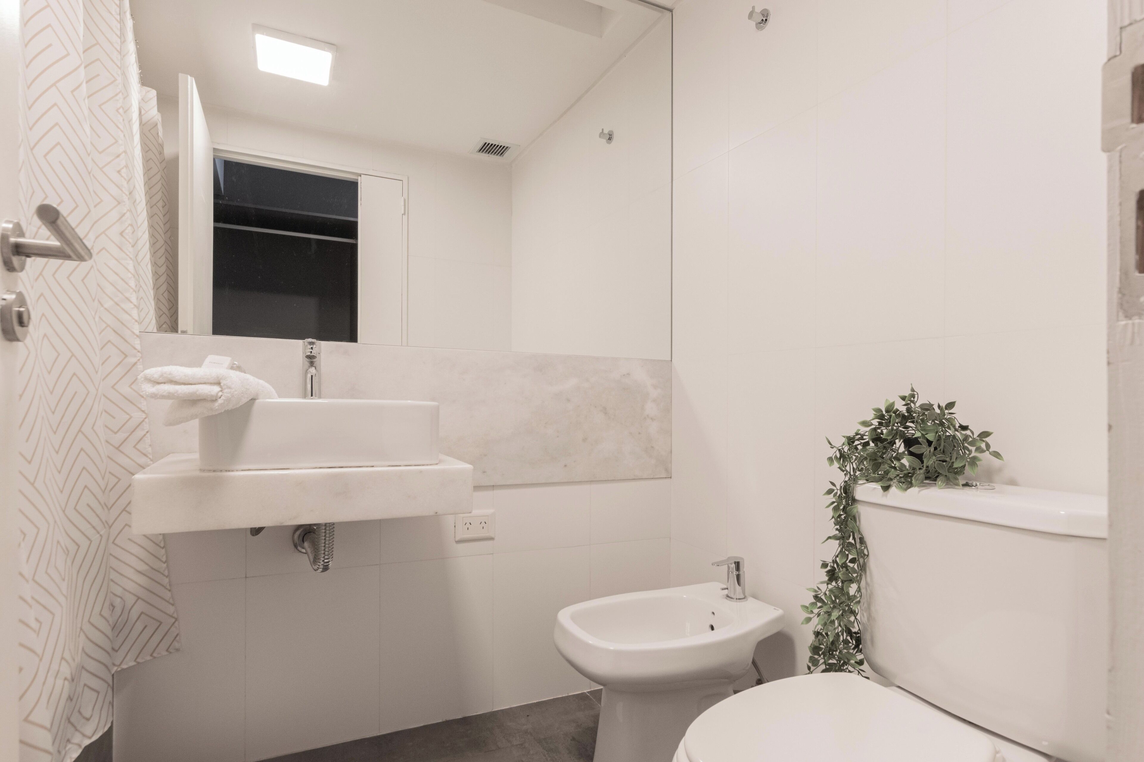 A bathroom with a sink, bidet, toilet, and a mirror.