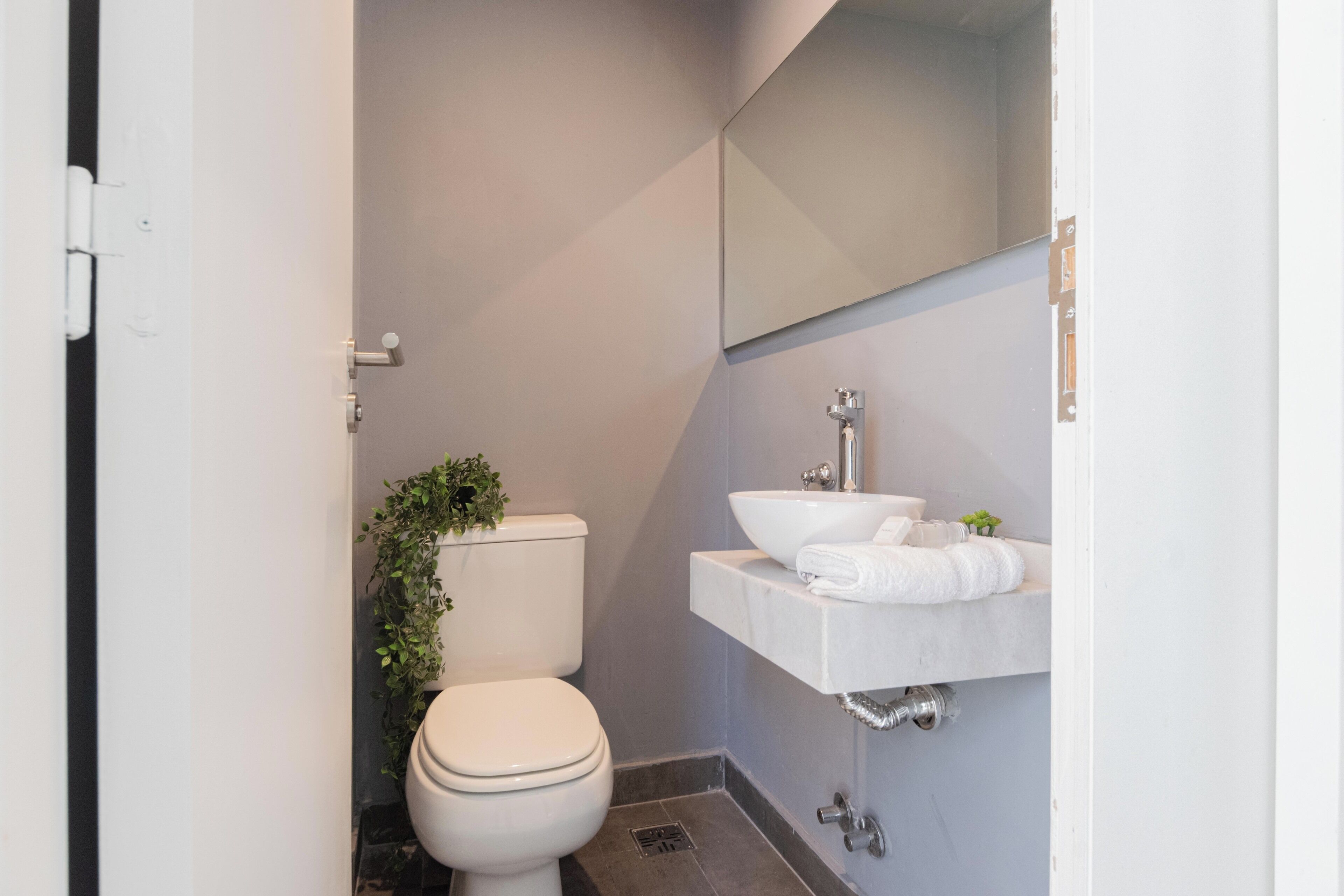 A small, modern bathroom with a toilet, a sink, and a mirror.