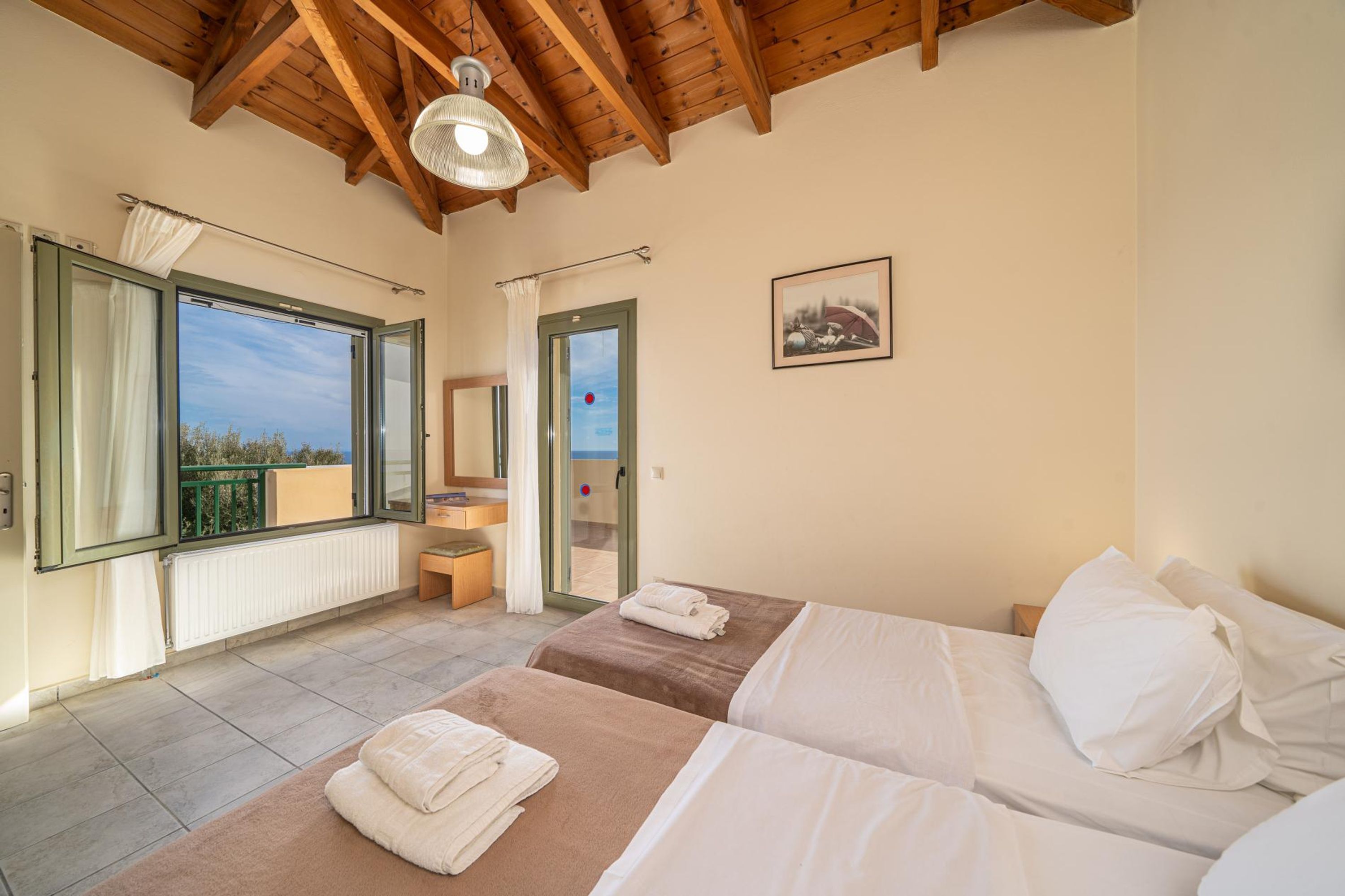 Ein Schlafzimmer mit zwei Betten, einem großen Fenster, einem Balkon und einem Badezimmer.