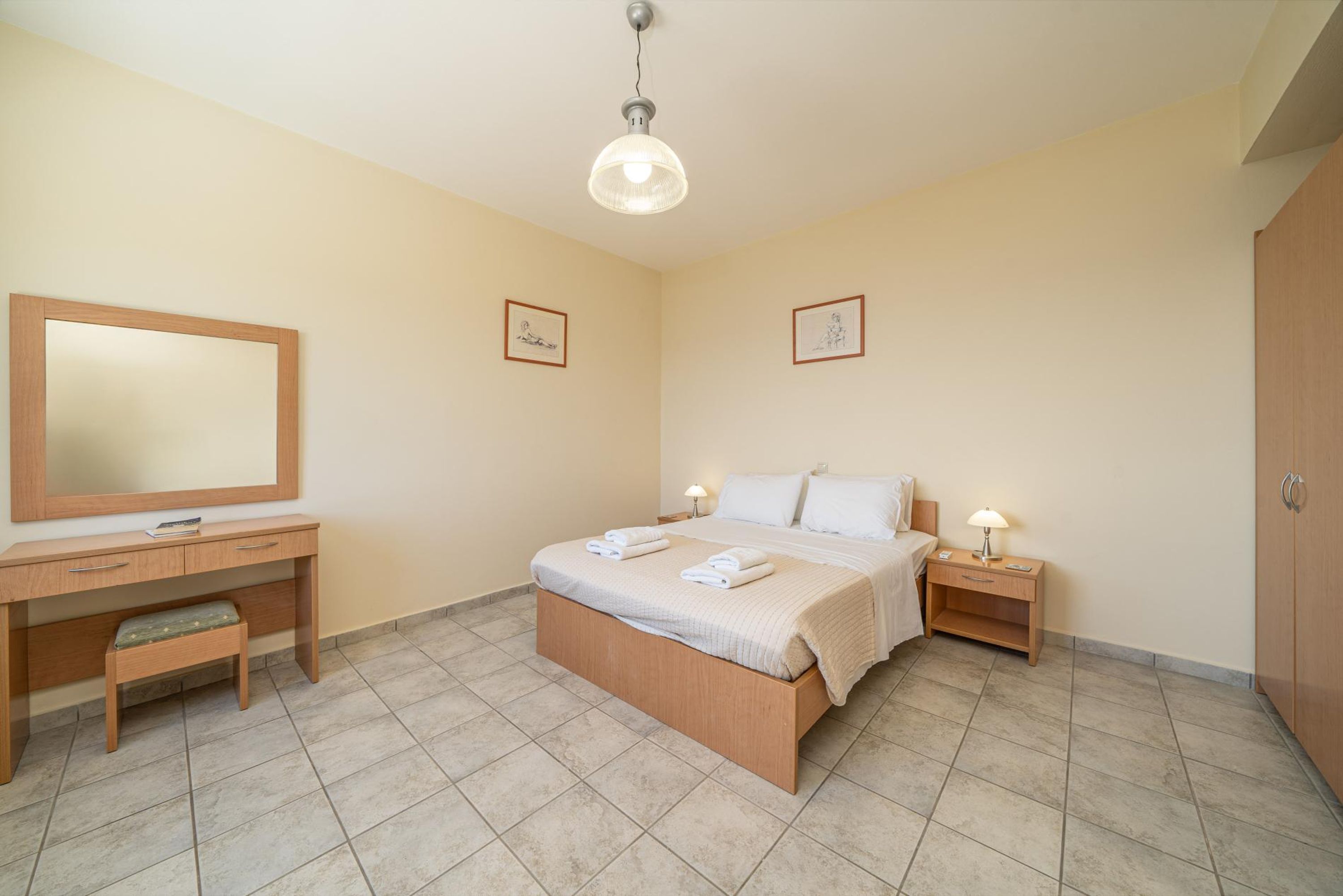 Ein Schlafzimmer mit Bett, Nachttischen, Schreibtisch, Stuhl und Kleiderschrank.