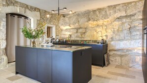 Eine moderne Küche mit einer großen Kochinsel, Steinwänden und einem eingebauten Backofen.