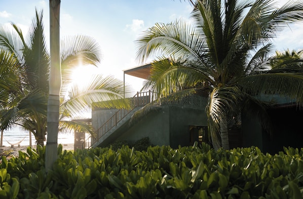 A coastal resort with palm trees, a concrete structure, and a view of the sea.