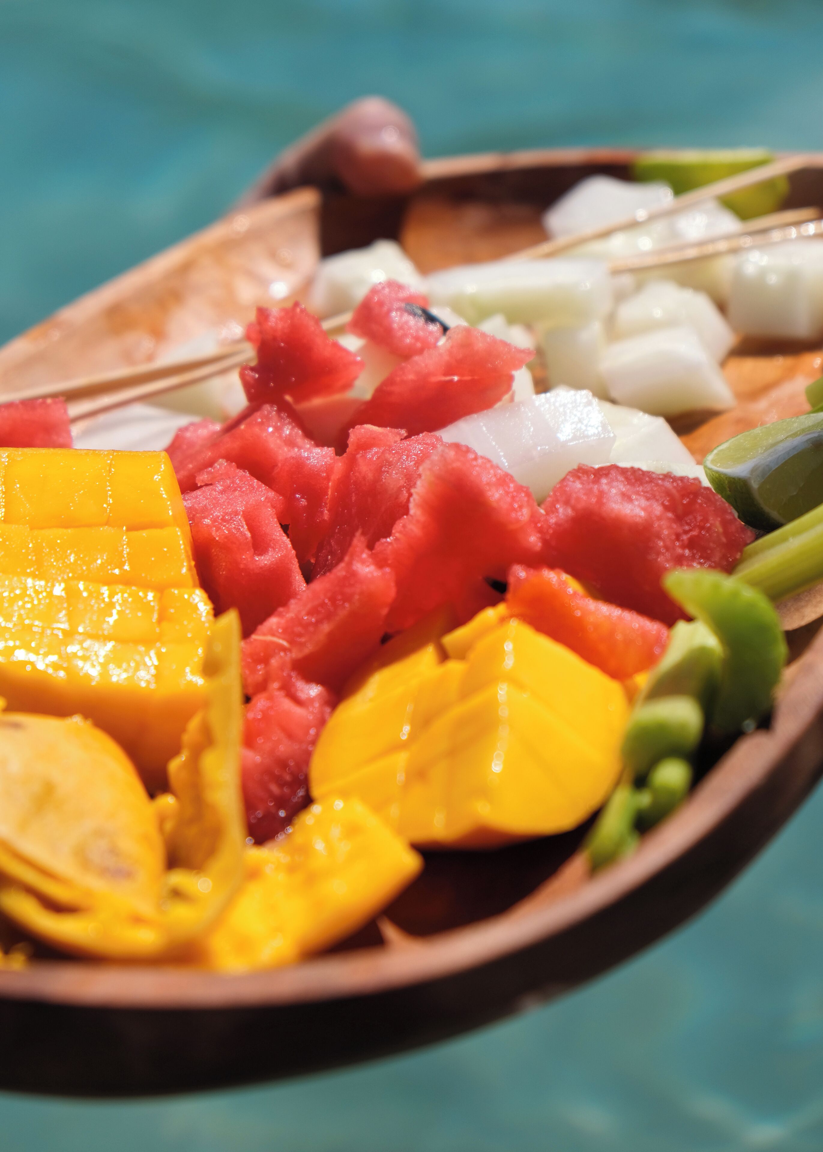 Una bandeja de madera con frutas y verduras diversas.