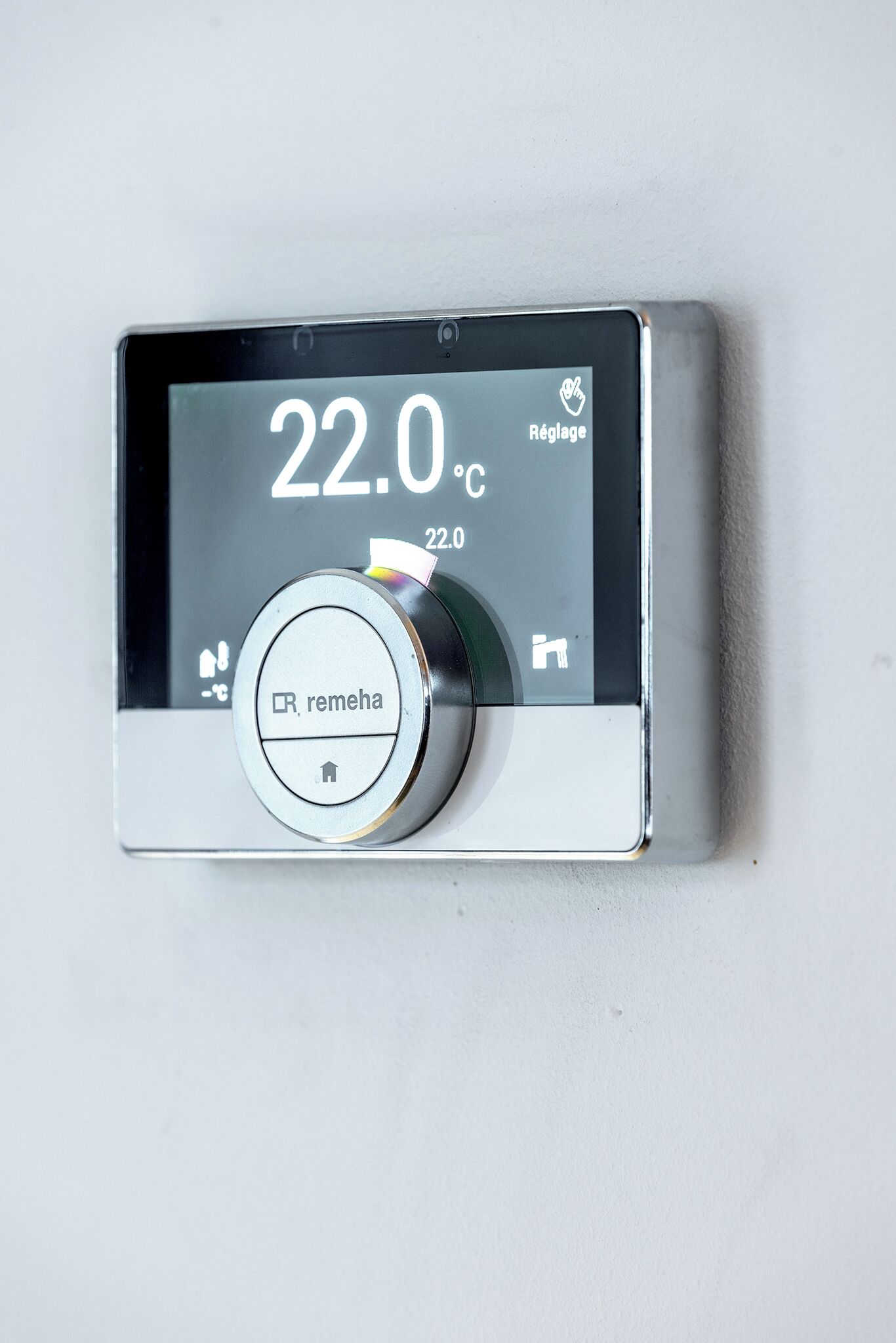 Termostato con pantalla digital que muestra 22.0°C, un botón de reinicio y un control remoto.