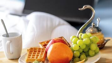 A breakfast setting with waffles, fruit, and a teapot on a table.