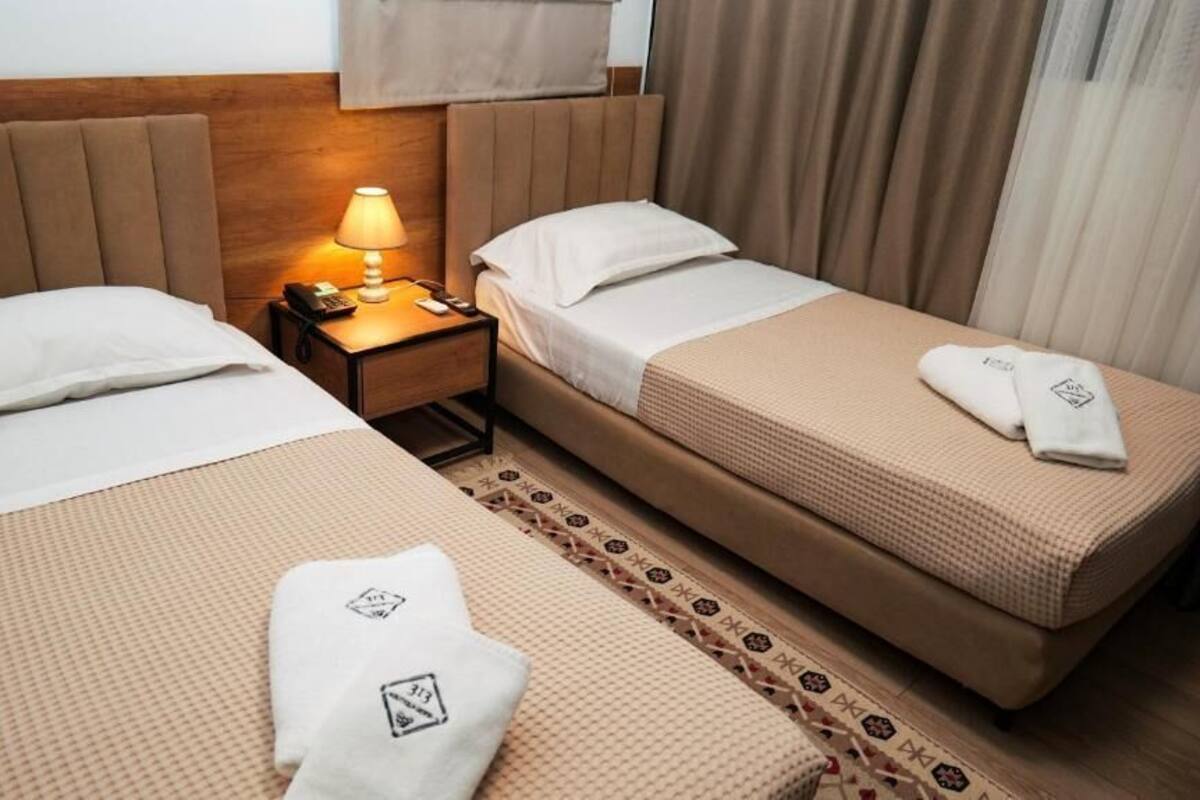 Une chambre d’hôtel avec deux lits, une table de chevet avec une lampe et un tapis à motifs.