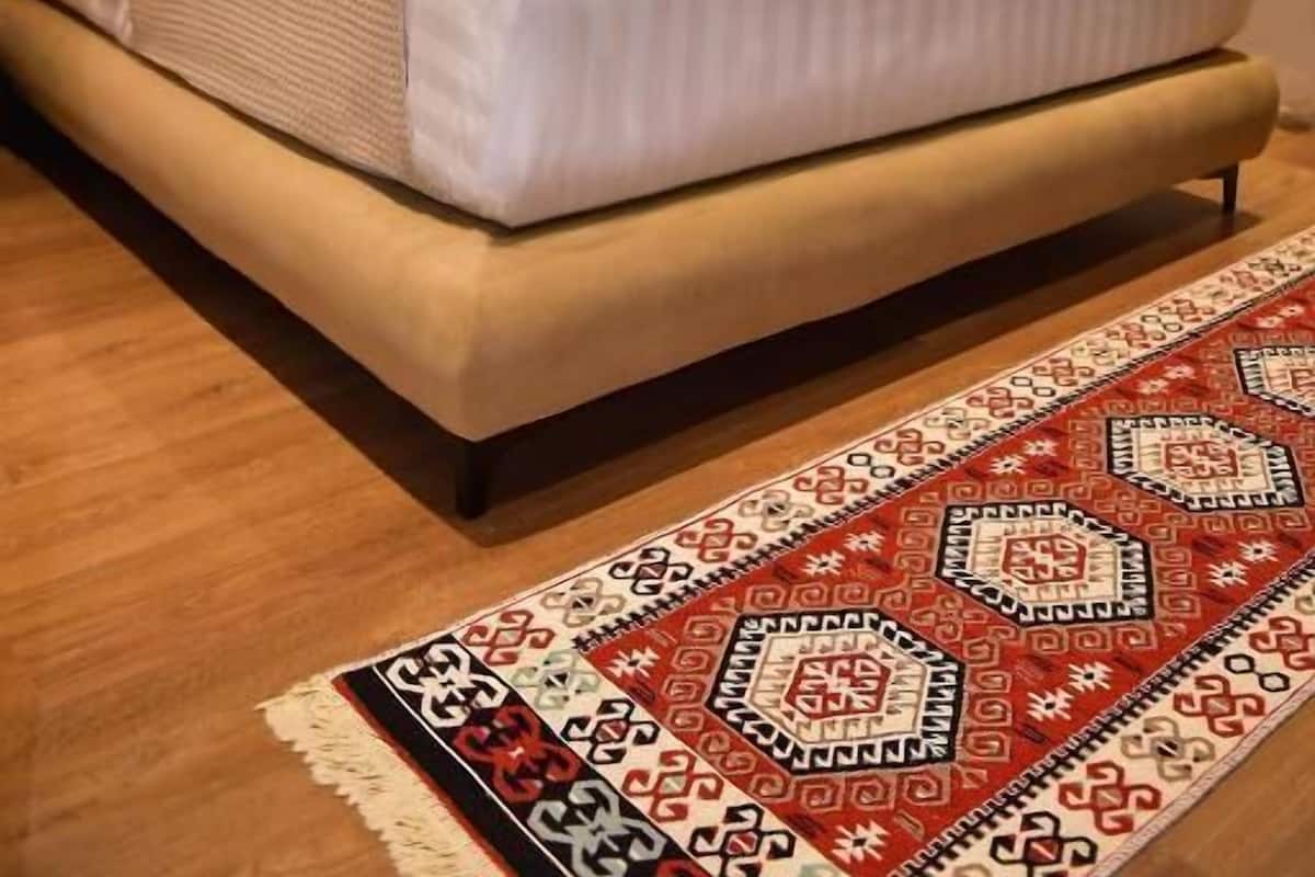 Une chambre à coucher avec un lit, une tête de lit en bois, une lampe de chevet et un tapis à motifs.
