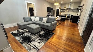 A modern living room with a sectional sofa, a coffee table, and a black and white rug. - Midnight Sanctuary at Mystic Falls - 3 Bed 2.5 BA Home 1 mi to Covington Square (Covington)