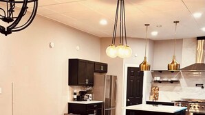 A modern living room with a grey sofa, a glass coffee table, and a black rug. - Midnight Sanctuary at Mystic Falls - 3 Bed 2.5 BA Home 1 mi to Covington Square (Covington)