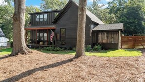 A two-story house with a porch, a flag, and a fenced yard. - Midnight Sanctuary at Mystic Falls - 3 Bed 2.5 BA Home 1 mi to Covington Square (Covington)