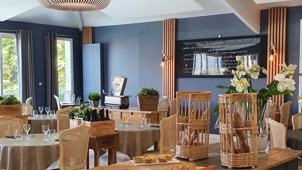 A restaurant with wooden tables, wicker chairs, and a chalkboard menu.