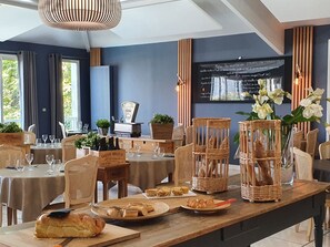 A restaurant with wooden tables, wicker chairs, and a chalkboard menu. - Hôtel restaurant bar les Voyageurs (Montaigu-Vendée)