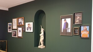 A wall with framed pictures and a statue.