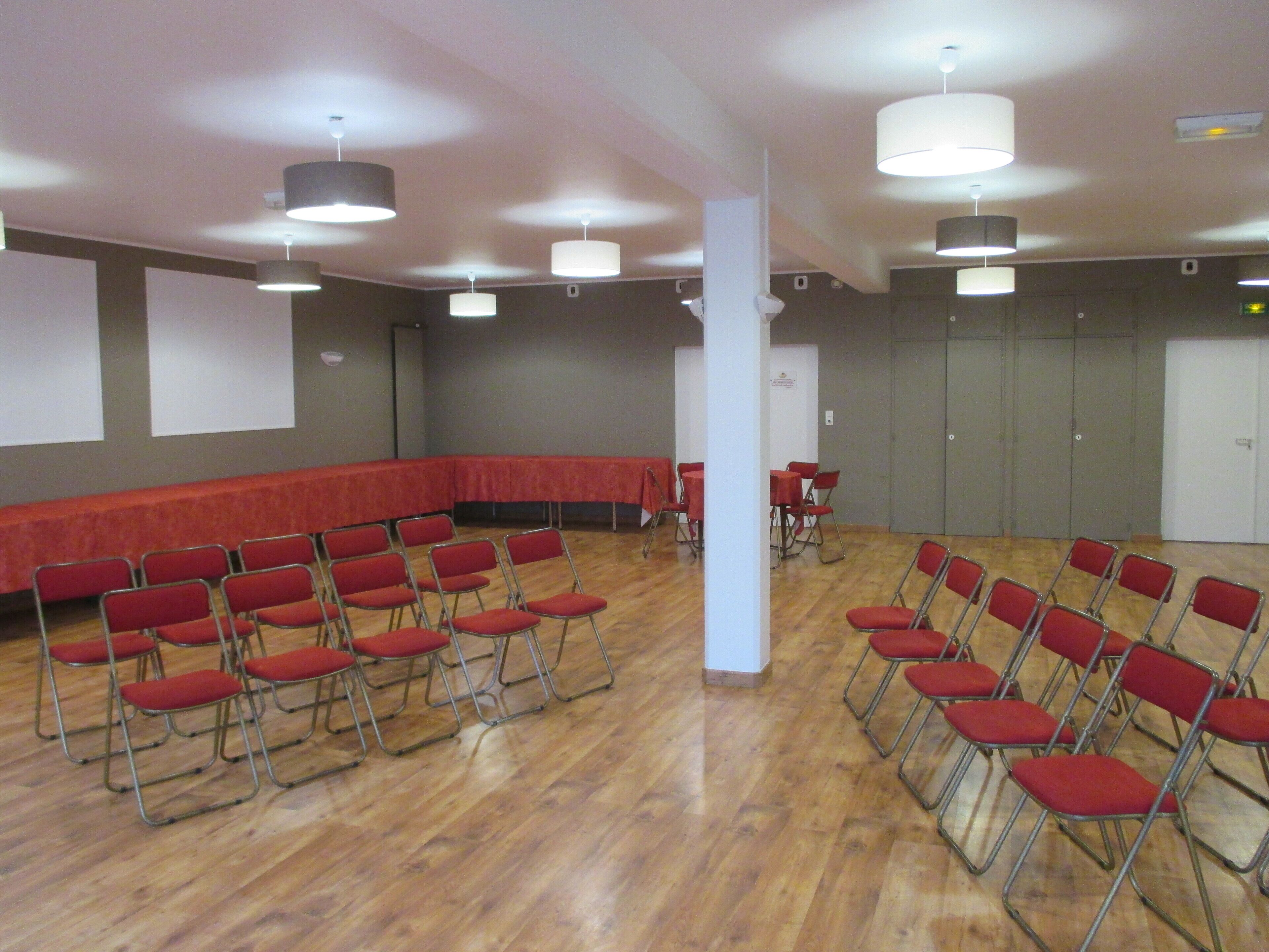 A conference room with foldable chairs, a long table, and a screen.