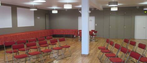 A conference room with foldable chairs, a long table, and a screen.