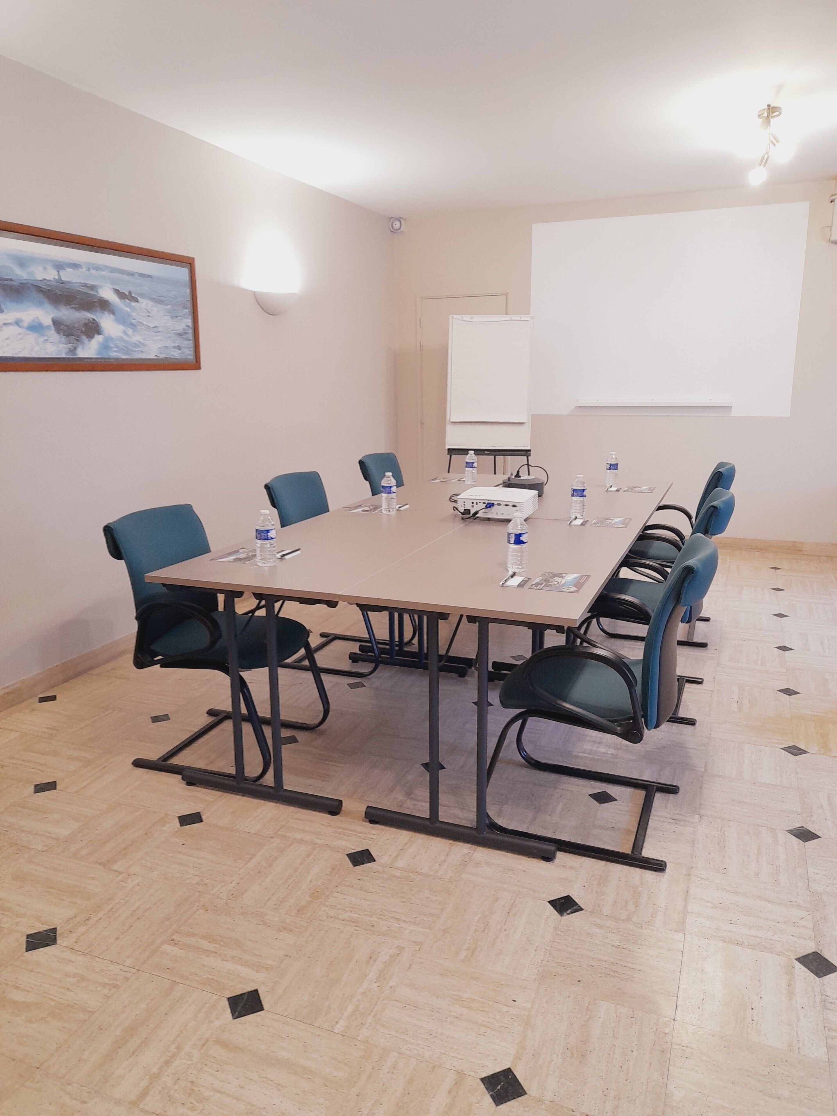 A conference room with a large table, chairs, a projector, and a whiteboard.