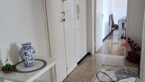Un pasillo con un aparador blanco, una alfombra estampada y una puerta que da a un comedor.