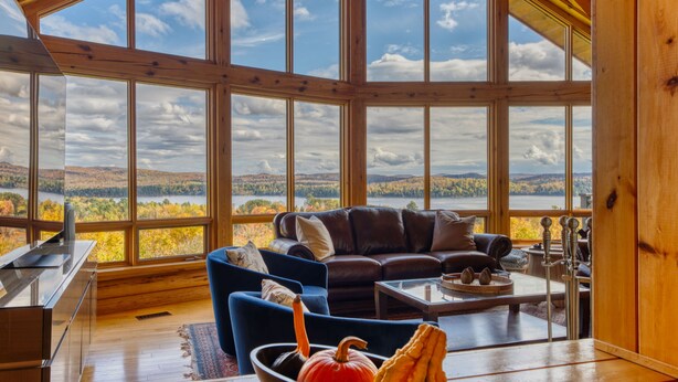Un salón amplio con un gran ventanal que ofrece una vista panorámica de colinas y árboles.