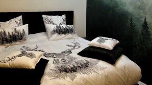 Une chambre à coucher avec un lit, une fresque murale sur le thème de la forêt et un lustre.