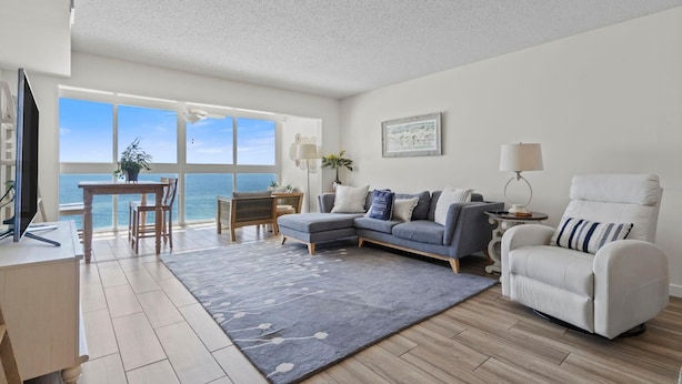 A living room with a sofa, armchair, and a dining area with a table and chairs. - Edgewater West 65 (Gulf Shores)