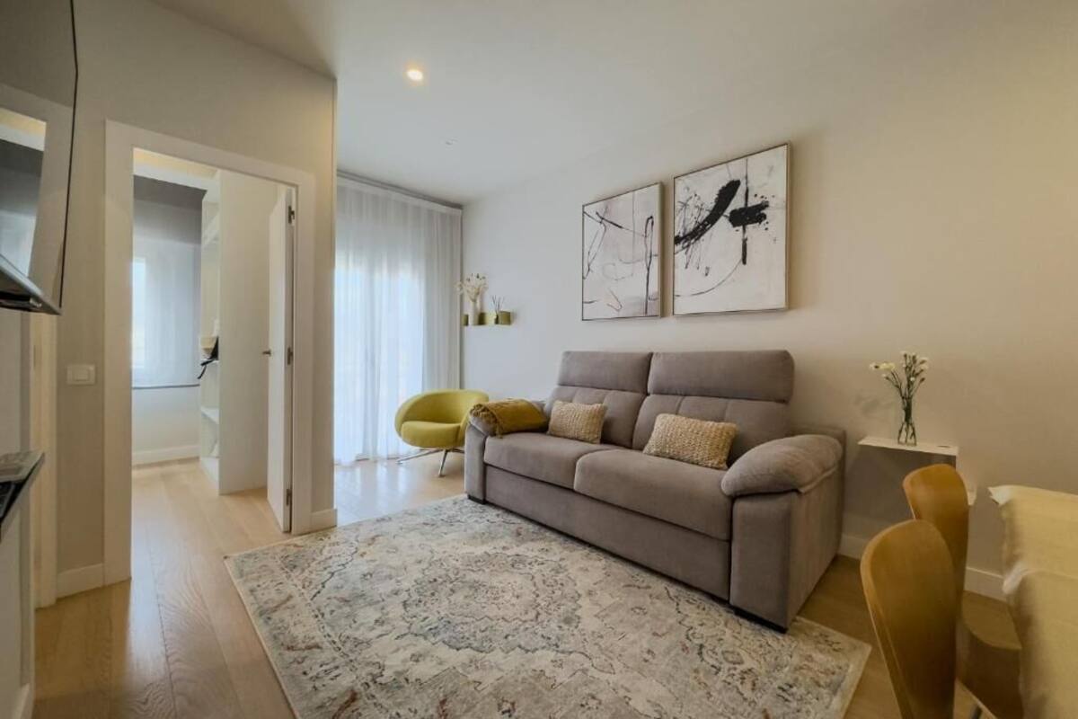 A living room with a sofa, a yellow chair, and abstract art on the wall.