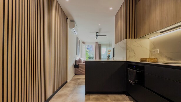 Una cucina moderna con isola centrale, elettrodomestici integrati e vista sull'area living adiacente.