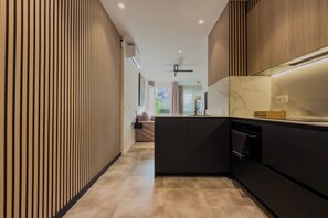 Une cuisine moderne dotée d’un îlot central, d’appareils électroménagers intégrés et offrant une vue sur l’espace de vie adjacent.