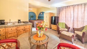 A living room with a dining area, a ceiling fan, a TV, wicker furniture, and a decorative vase with flowers. - 7bdrm  boutique hotel with AC, WiFi , heated pool convenient location. (Loreto)