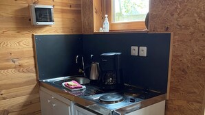 Eine kompakte Küche mit integriertem Kühlschrank, einer Kaffeemaschine und einem Fenster über der Spüle.