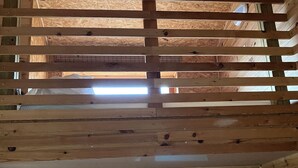 Ein Zimmer mit Holzbalkendecke, sichtbaren Holzbalken und einer Wand, die mit Holzspänen verkleidet ist.