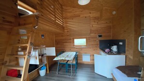 Eine gemütliche Holzhütte mit Essecke, Küchenzeile und einem Bett.