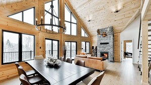 A spacious dining area with a large wooden table and chairs, a fireplace, and a view of the outdoors. - Magnificent ski-in/out wooden chalet in Mont-Blanc with SPA and billiard table! (Mont-Blanc)