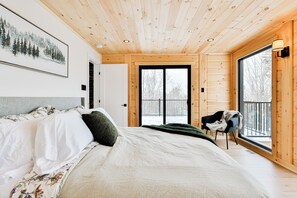 Relax in a serene bedroom with a large bed, framed artwork, and a window offering a view of the outdoors.